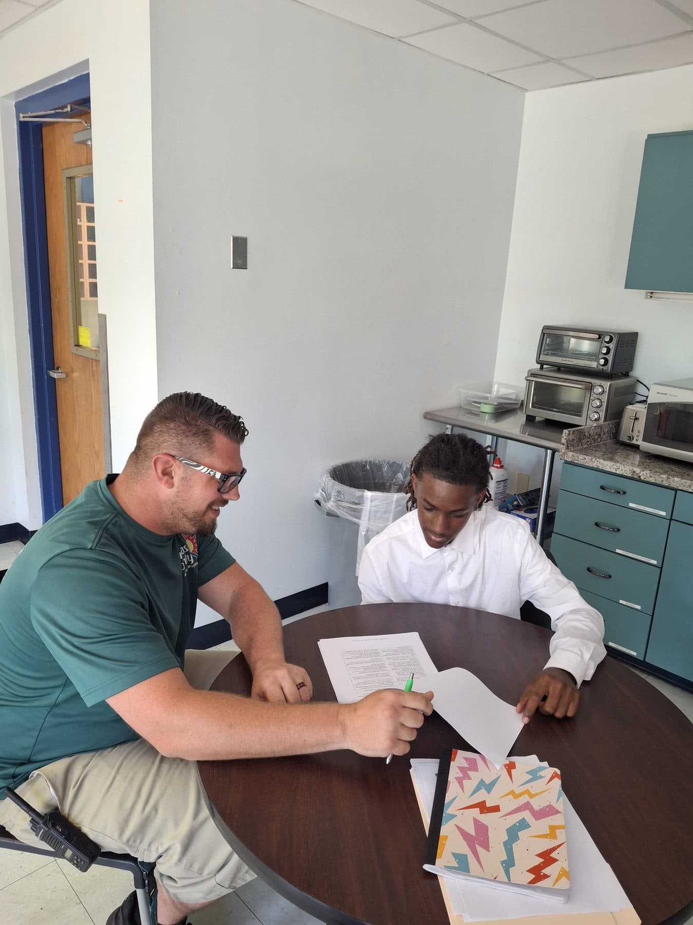 A job coach walking a student through a work document one-on-one