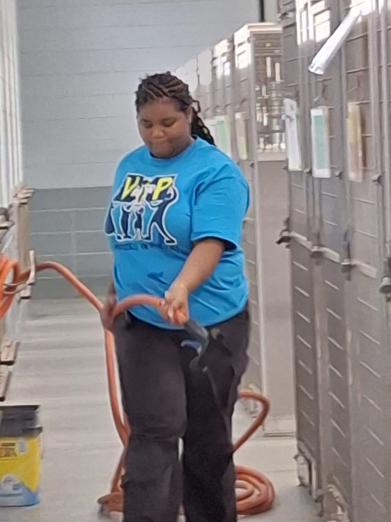 A participant coiling an extension cord in the kennel corridor at a worksite
