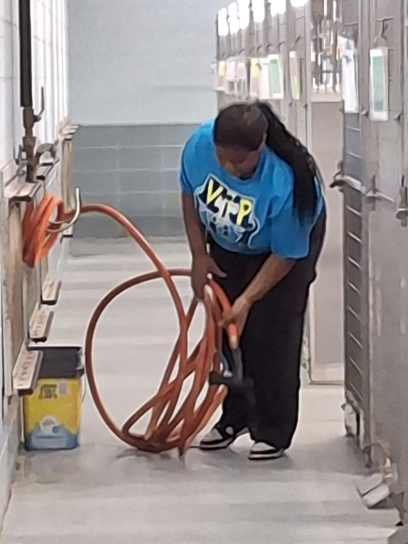 A participant coiling an extension cord while handling equipment at an animal-care worksite